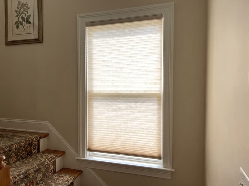 Honeycomb cellular shade on a stairwell landing window in a traditional two-storey house in Buford