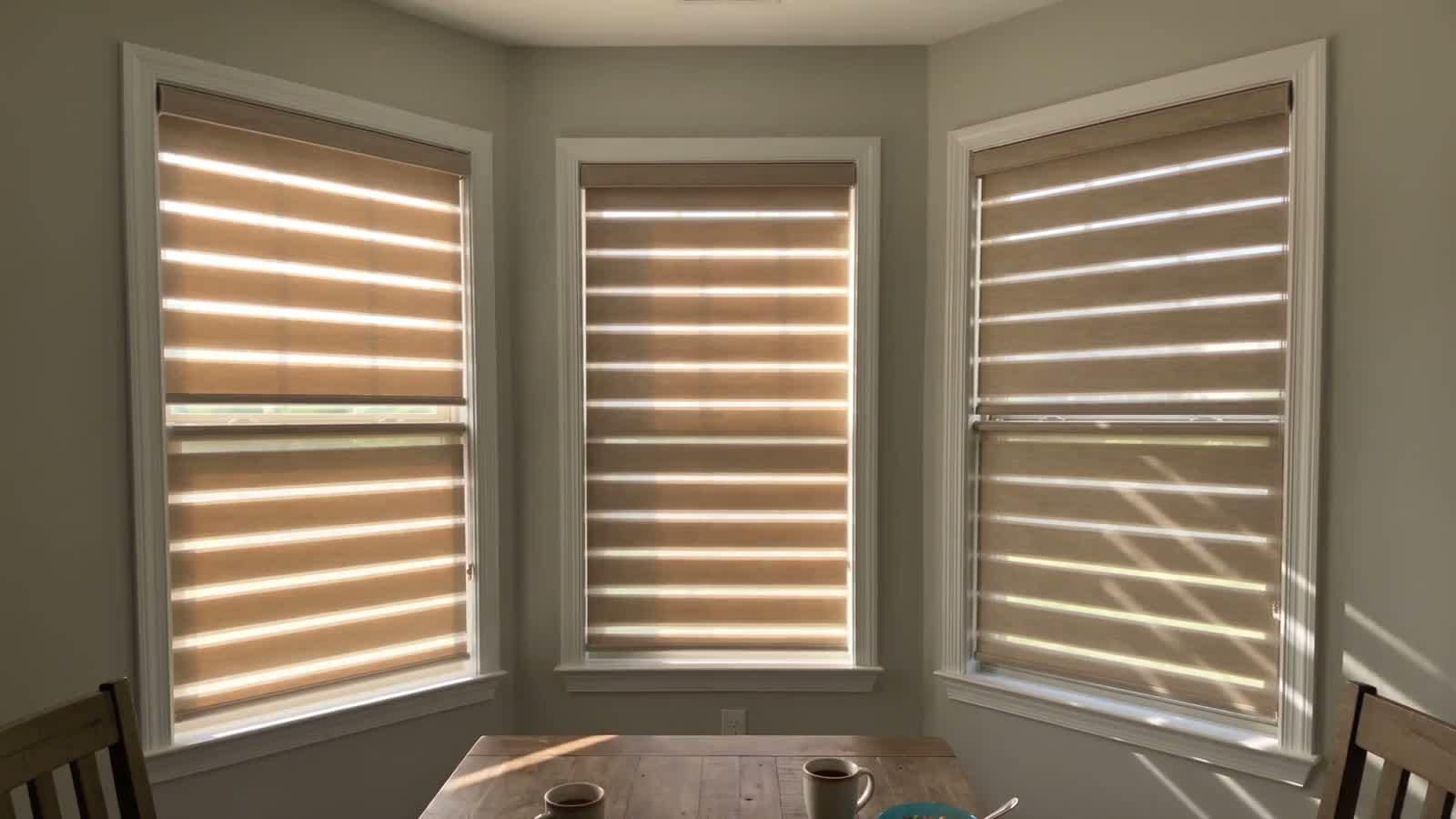 A motorised blackout roller shade part-way down a sunlit bedroom window